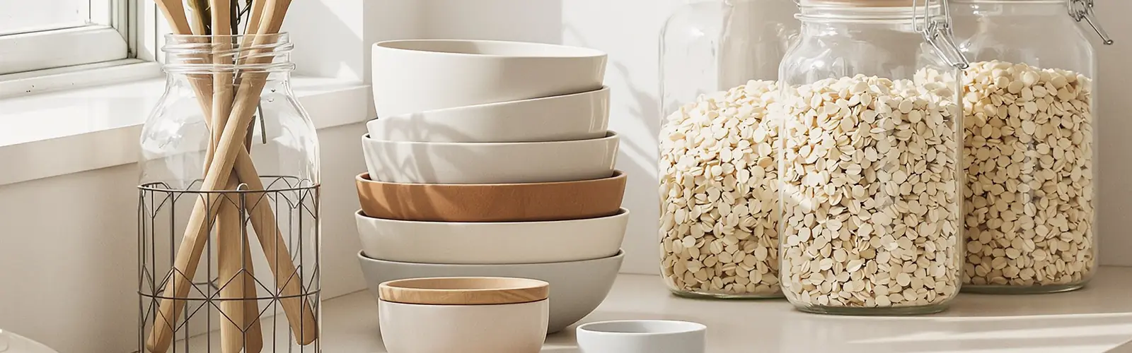 A quiet kitchen counter with ceramic bowls and glass jars